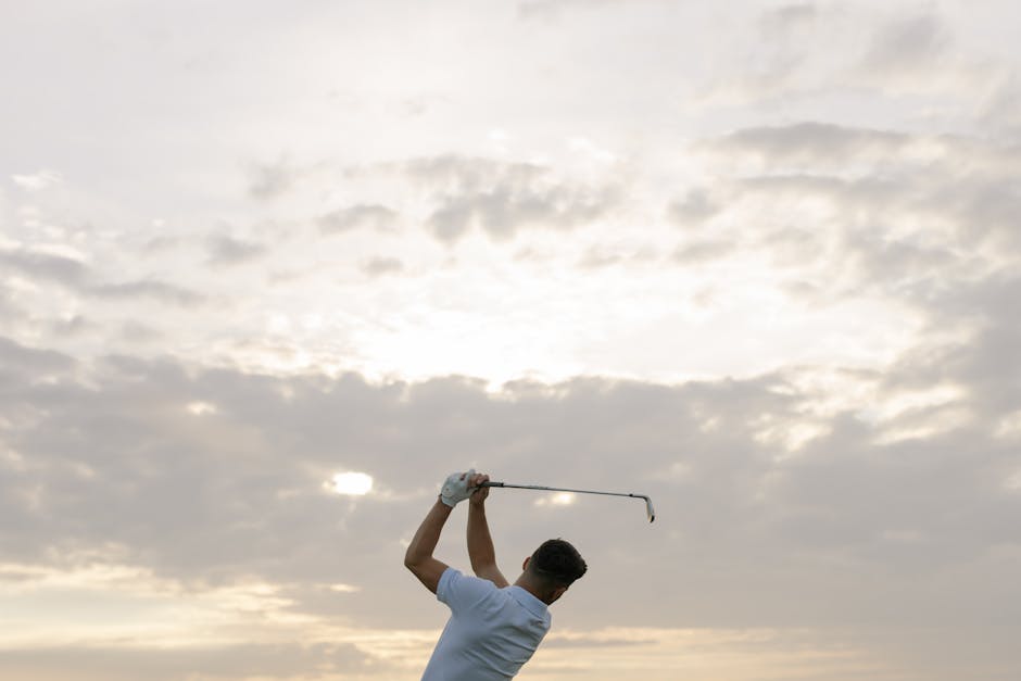A golfer swings his club against a dramatic cloudy sky, capturing the essence of the sport.