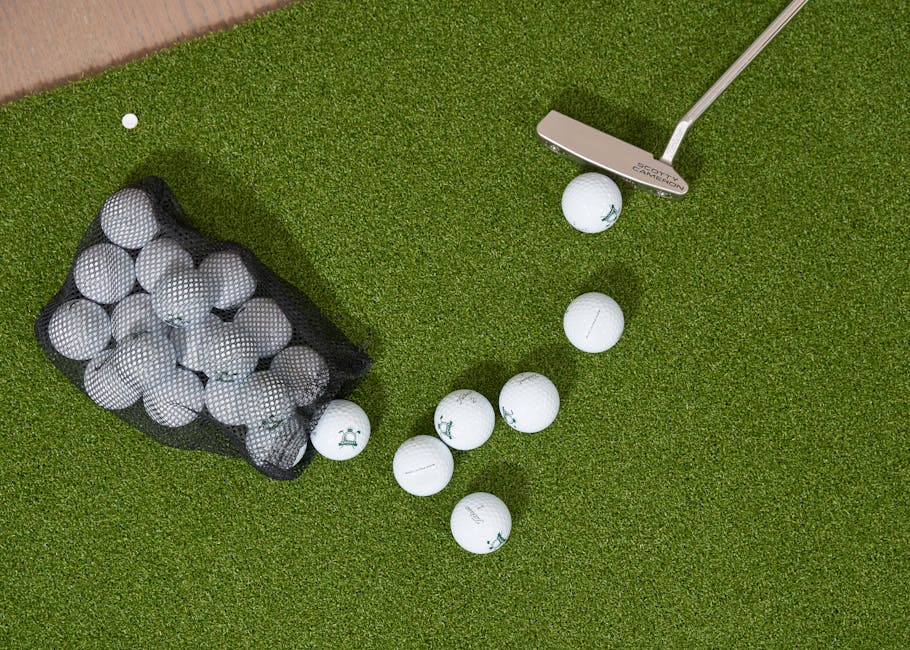 Overhead shot of golf balls, putter, and bag on a putting green turf.